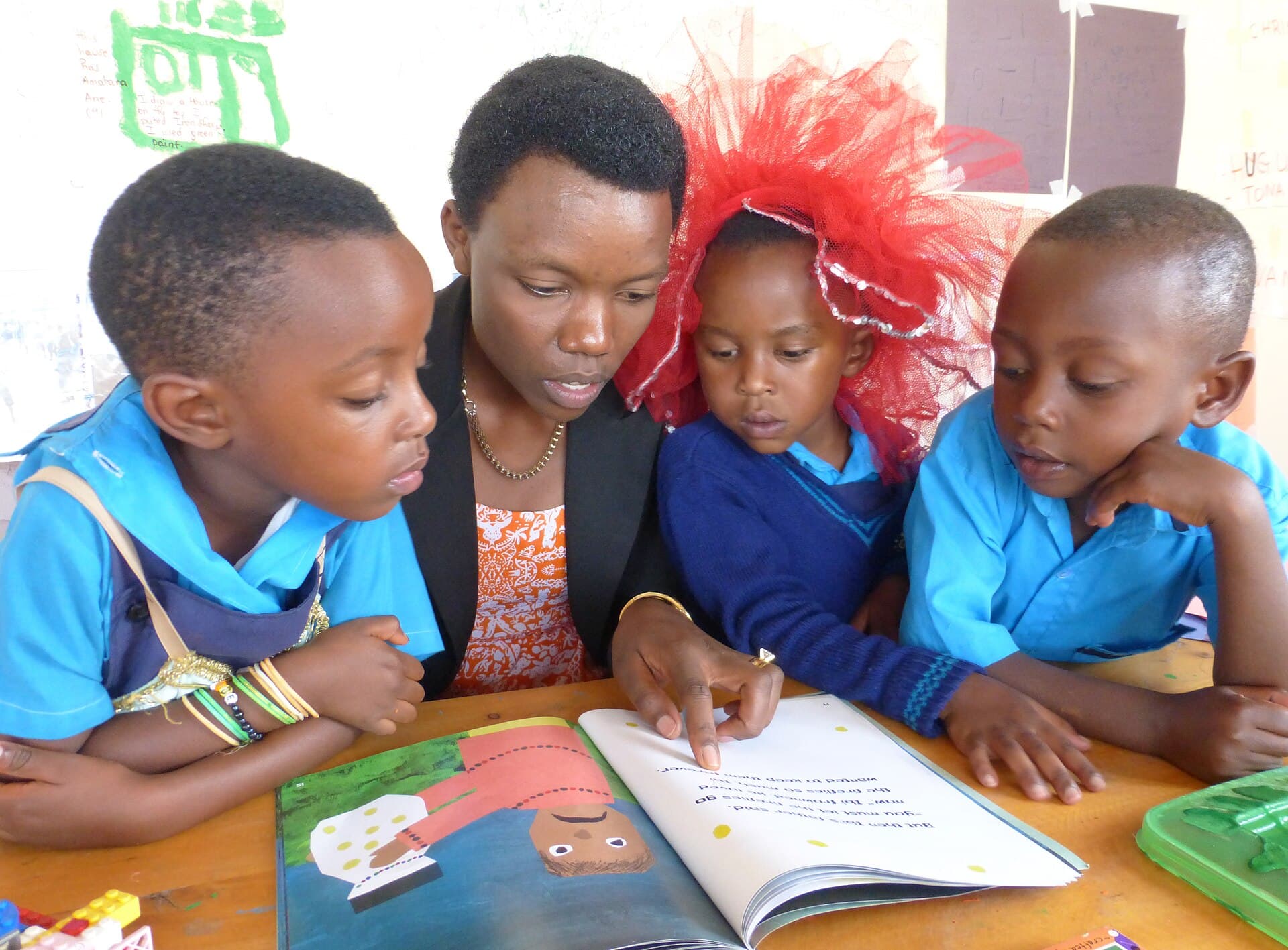 A teacher reading a picture book with three young children